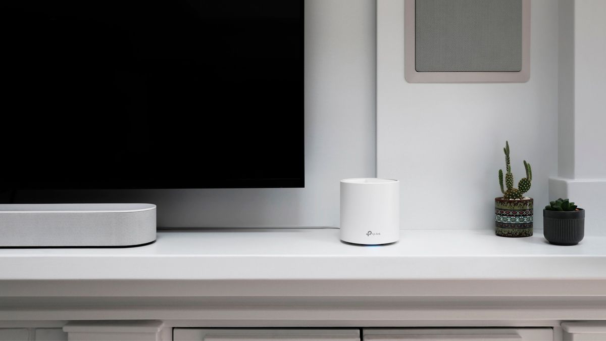 Um nó de malha Wi-Fi TP-Link Deco localizado próximo a uma TV.