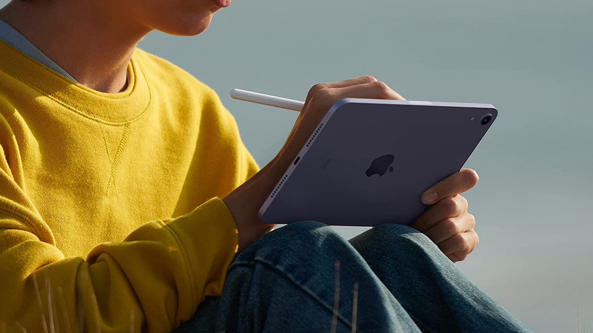 Pessoa com camisa amarela usando um tablet Apple com uma caneta stylus.