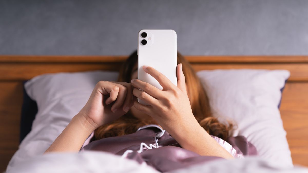 Mulher usando smartphone na cama