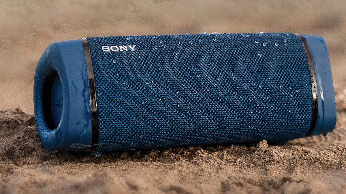 Alto-falante Bluetooth Sony SRS-XB33 sentado em uma praia arenosa