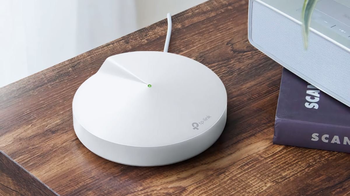 TP-Link Deco Mesh Wi-Fi Puck sentado em uma mesa ao lado de dois livros empilhados