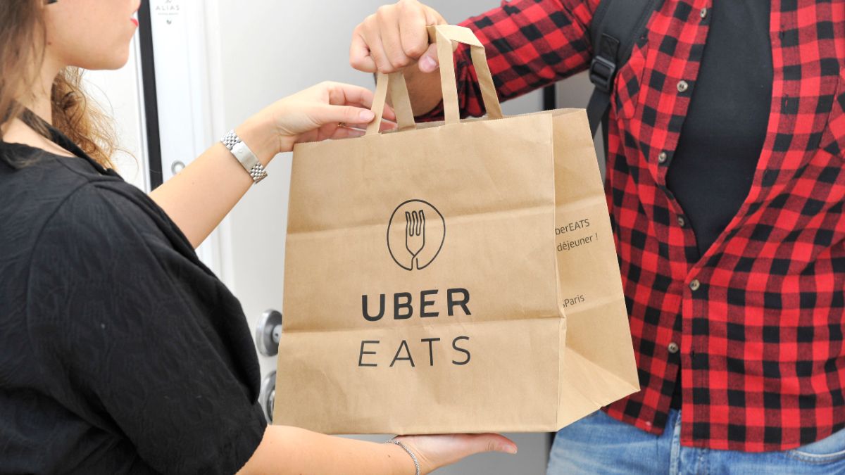 Mulher entregando um pedido do Uber Eats para um homem
