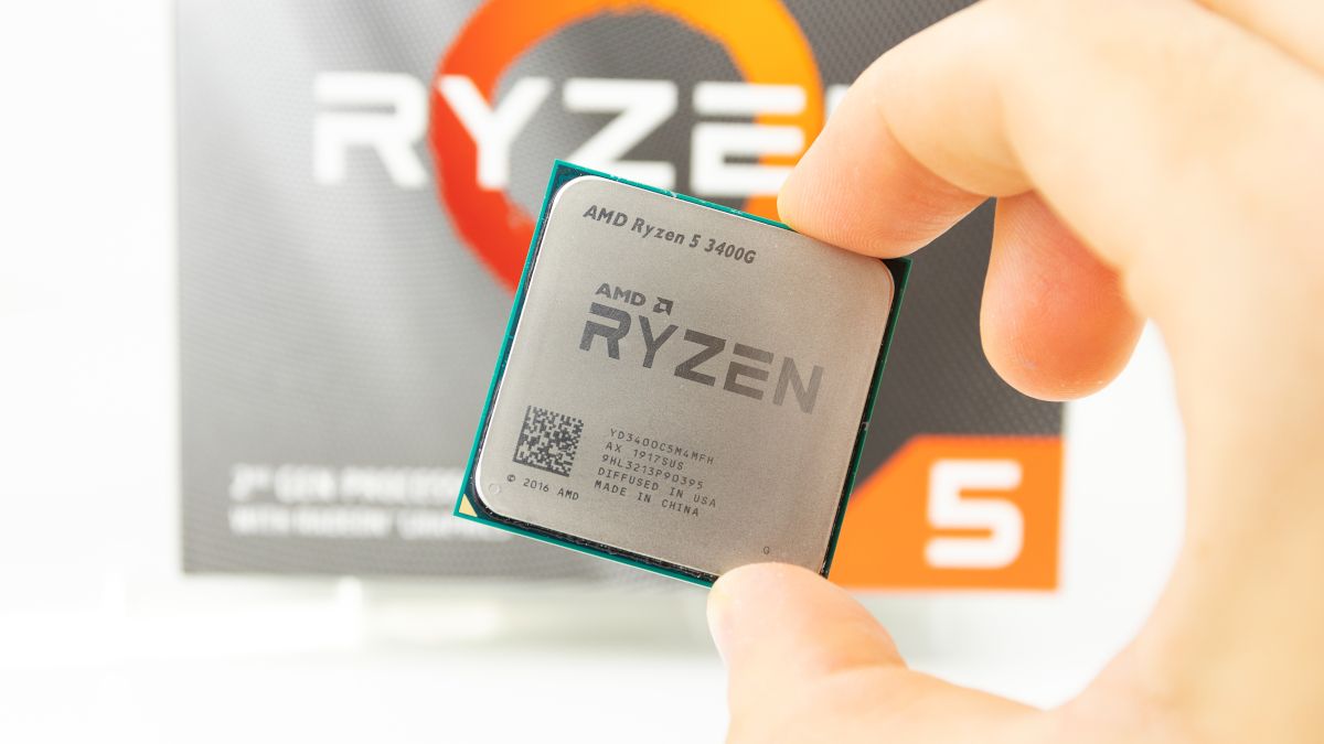 Close de uma CPU AMD Ryzen 5 3400G segurada entre os dedos de uma pessoa.