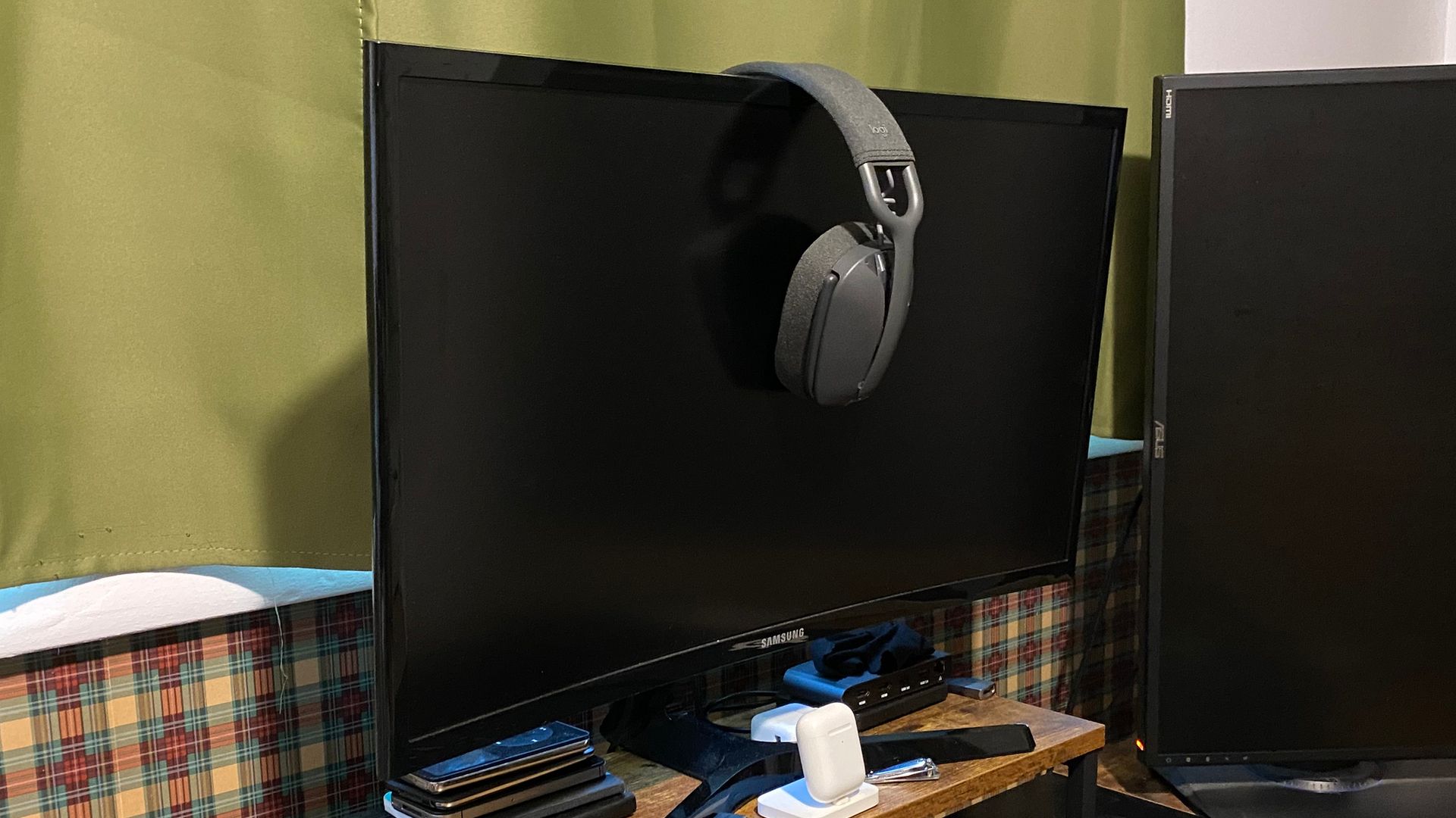 Logitech Zone Vibe 100 pendurado em um monitor curvo.