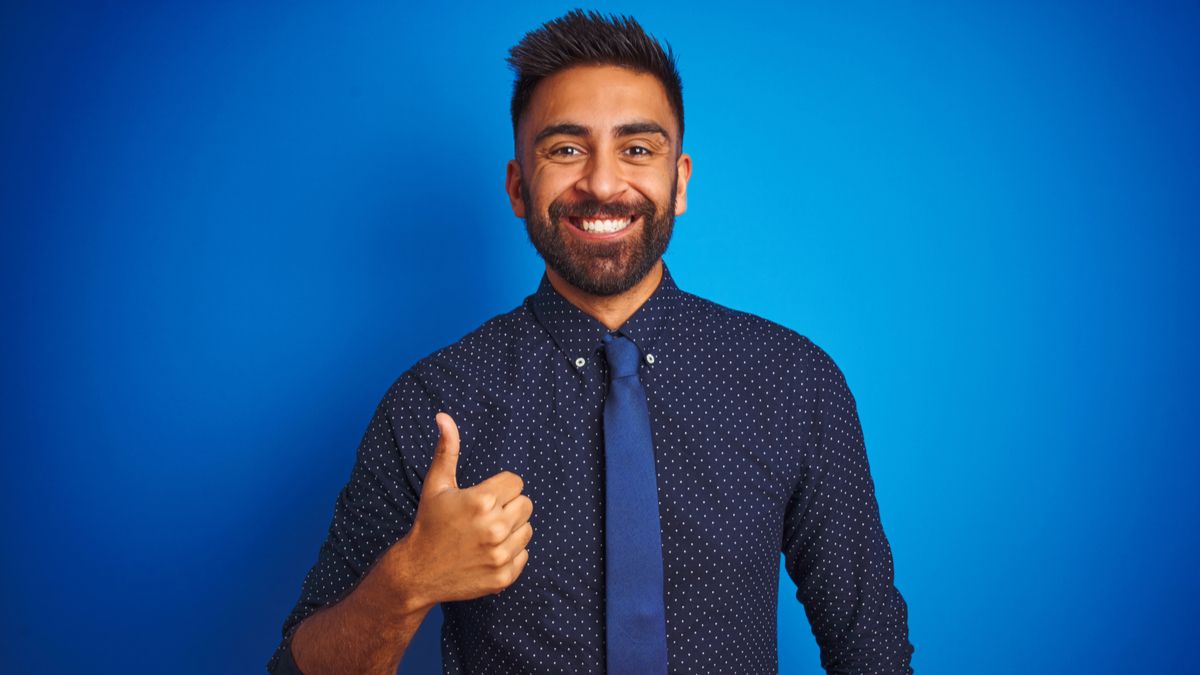 Empresário sorrindo e fazendo um gesto de positivo.