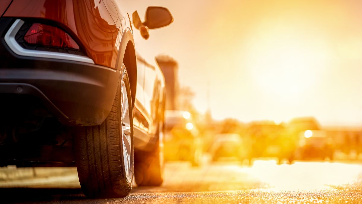 As rodas de um carro à luz quente de um pôr do sol de verão.