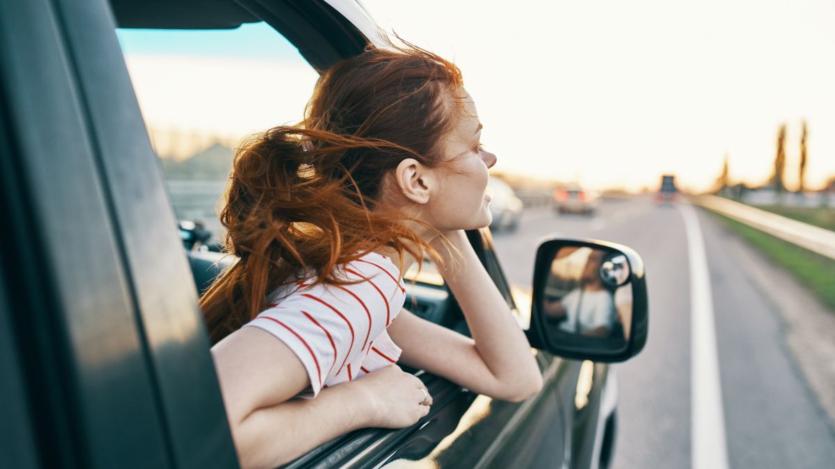 Mulher inclinada para fora da janela do carro.