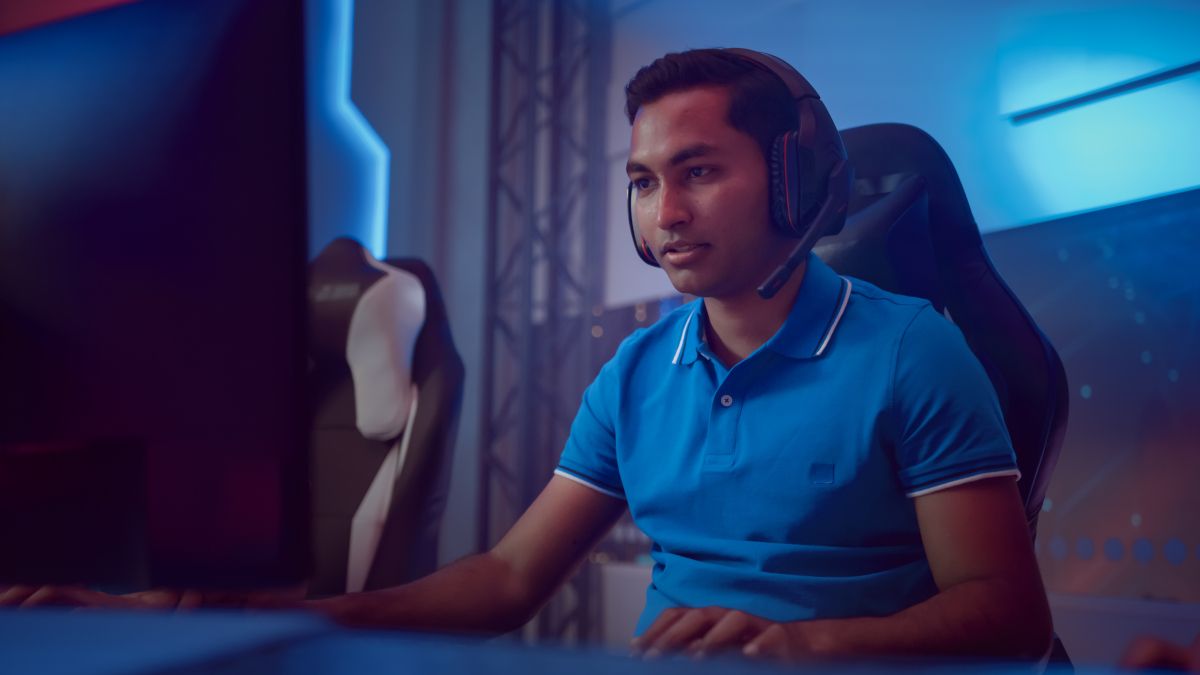 Jogador masculino de e-sports usando fone de ouvido olhando para o monitor