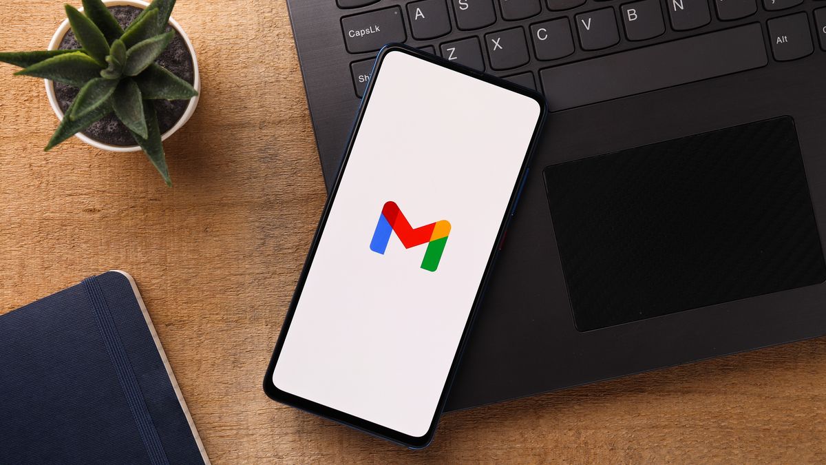 Logotipo do Gmail em um smartphone próximo a um computador