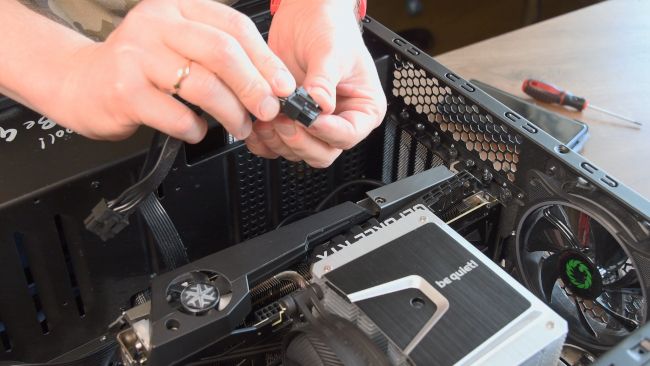 Mãos de uma pessoa inspecionando o plugue do cabo PCIe antes de conectar uma GPU.
