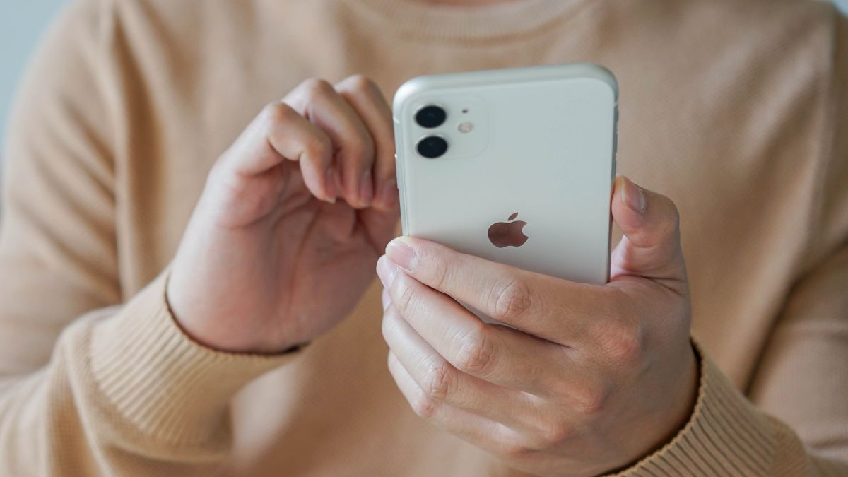 Close das mãos de um homem segurando um iPhone 11.