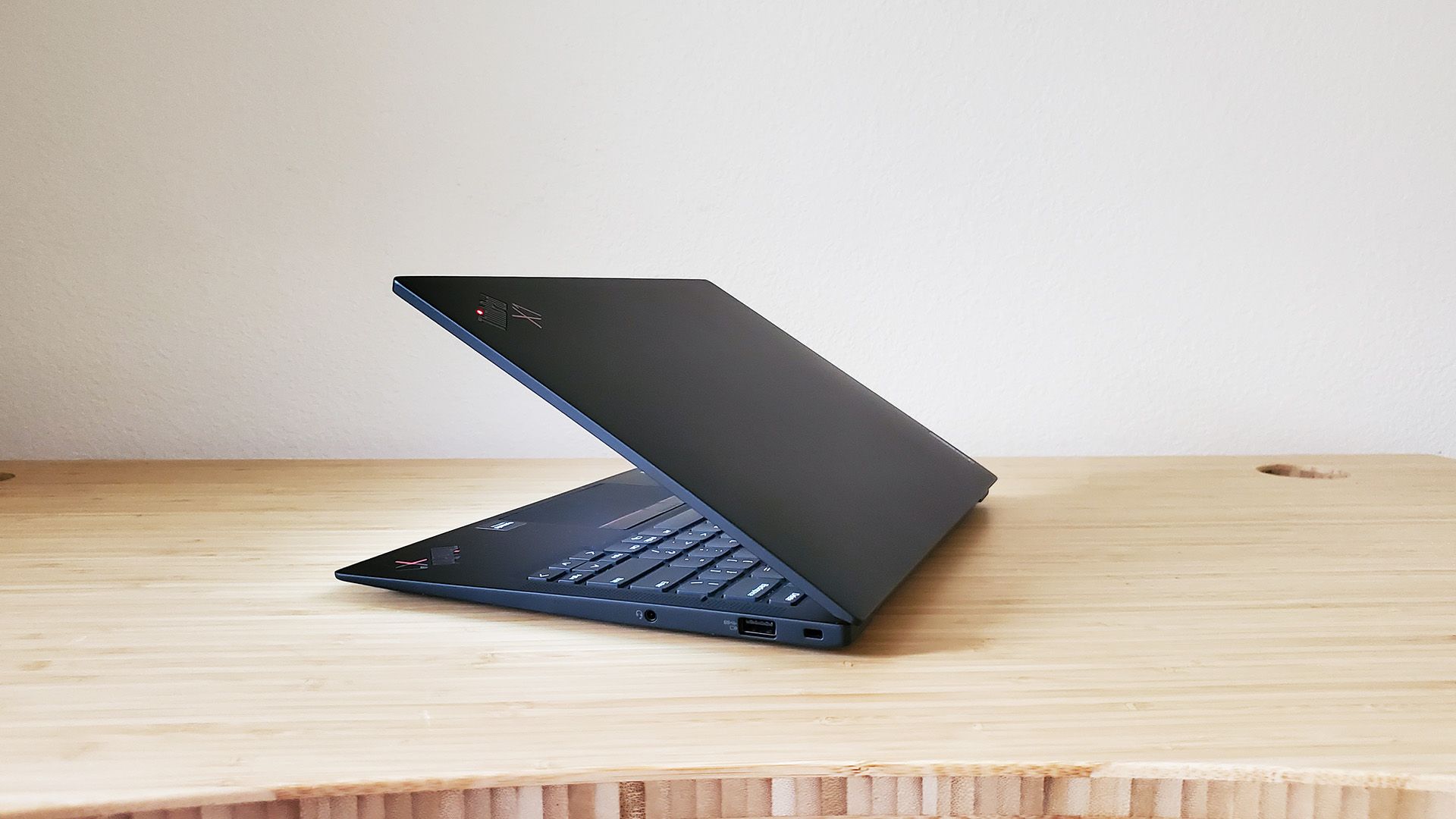 O laptop Lenovo ThinkPad X1 Carbon meio aberto sobre uma mesa.