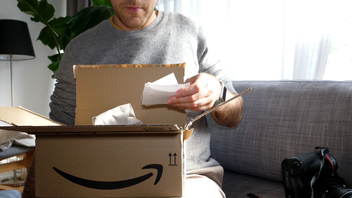 Homem abrindo um pacote da Amazon e lendo o recibo do pedido.