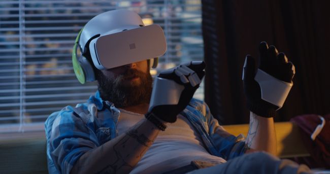 Homem usando um fone de ouvido de realidade virtual e luvas de exoesqueleto.
