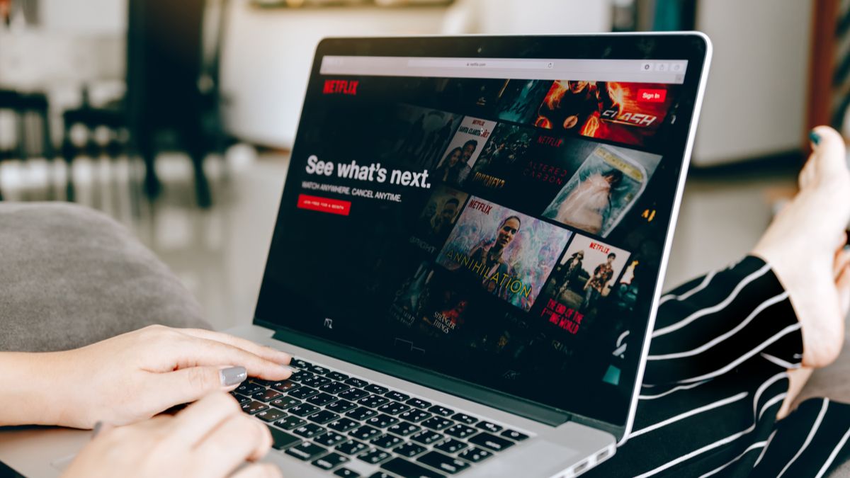Laptop no colo de uma pessoa, com o site da Netflix visível em um navegador.