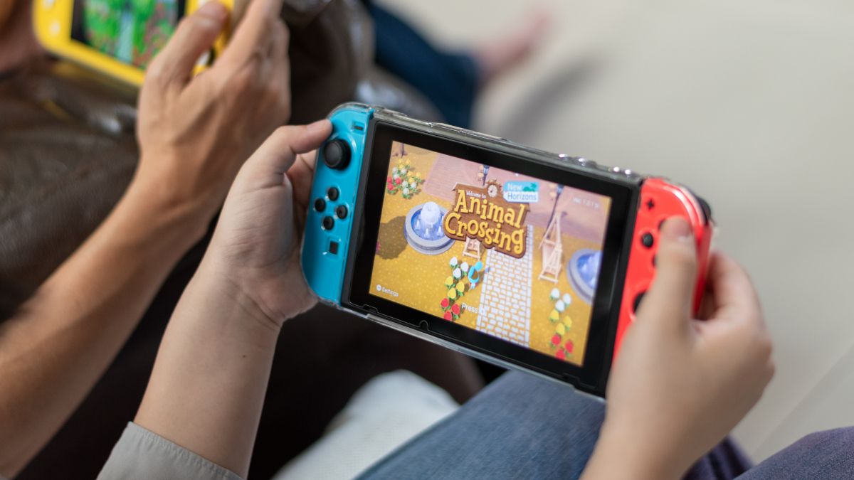 As mãos de uma pessoa segurando um Nintendo Switch com Animal Crossing visível na tela.