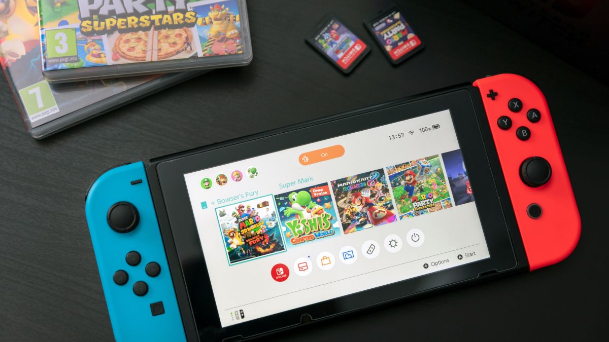 Uma consola Nintendo Switch numa mesa ao lado de dois cartuchos de jogos e respetivas caixas.