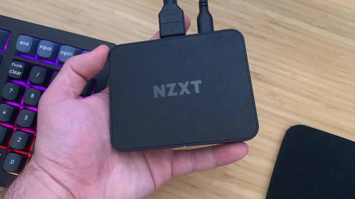 Placa de captura NZXT Signal 4K30 segurada na mão sobre a mesa