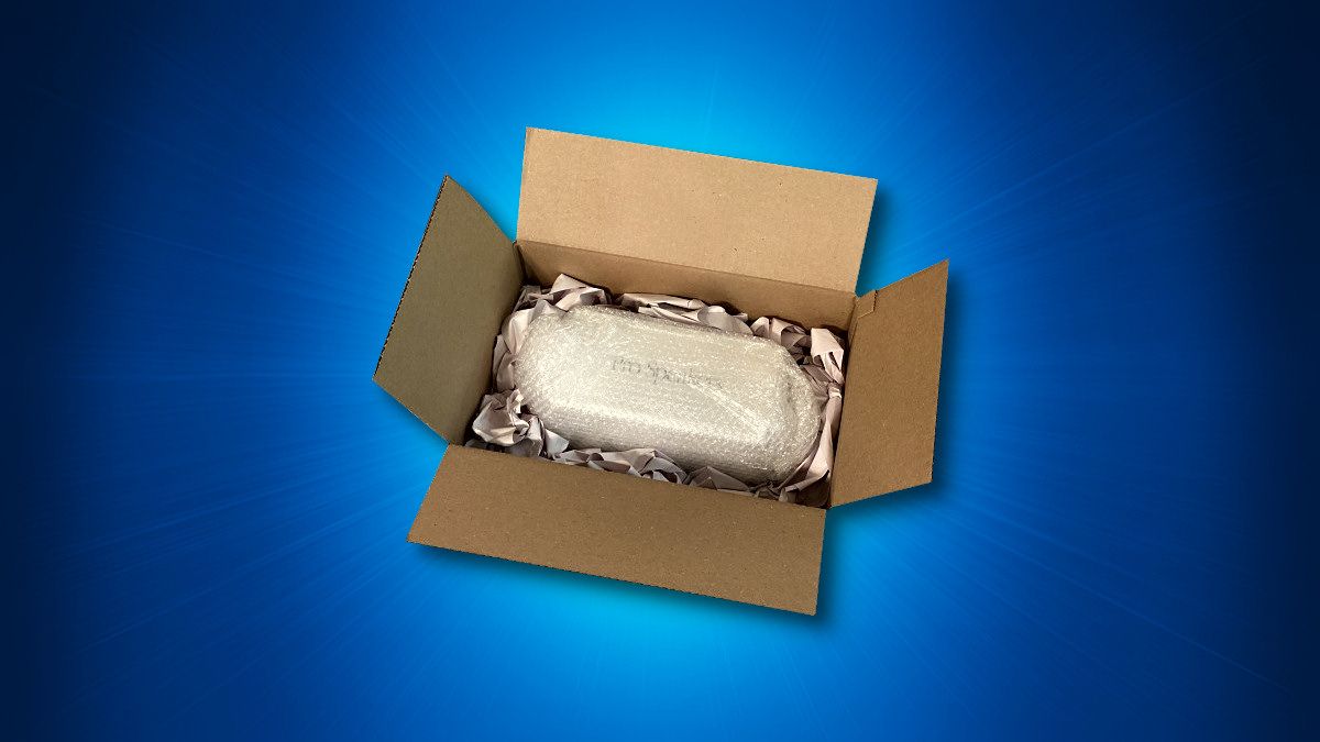 Um item eletrônico frágil ou volumoso sendo embalado para envio em uma caixa com fundo azul.
