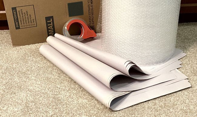 Os materiais de embalagem de que você precisará: caixa de papelão, papel de jornal, plástico bolha e fita adesiva.