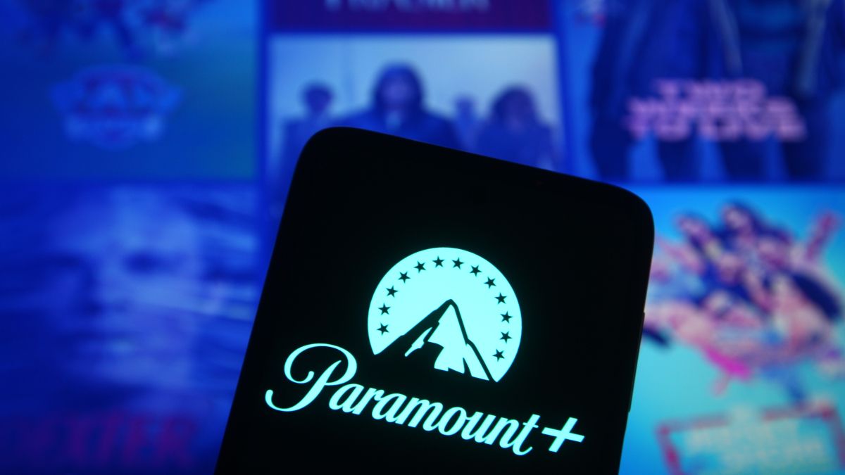 Logotipo da Paramount+ em um smartphone na frente de vários pôsteres de mídia