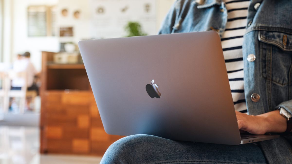 Pessoa usando um MacBook no colo em uma cafeteria