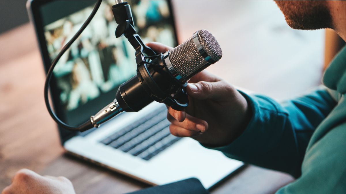 Homem usando um microfone durante streaming com um laptop.