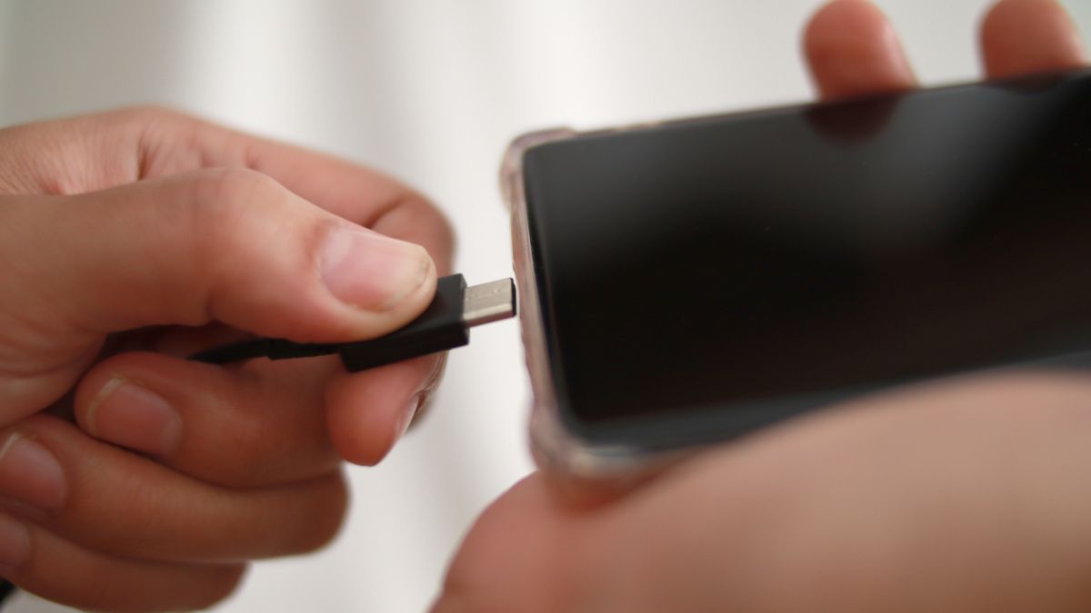 Close de uma pessoa conectando um cabo USB em um smartphone.