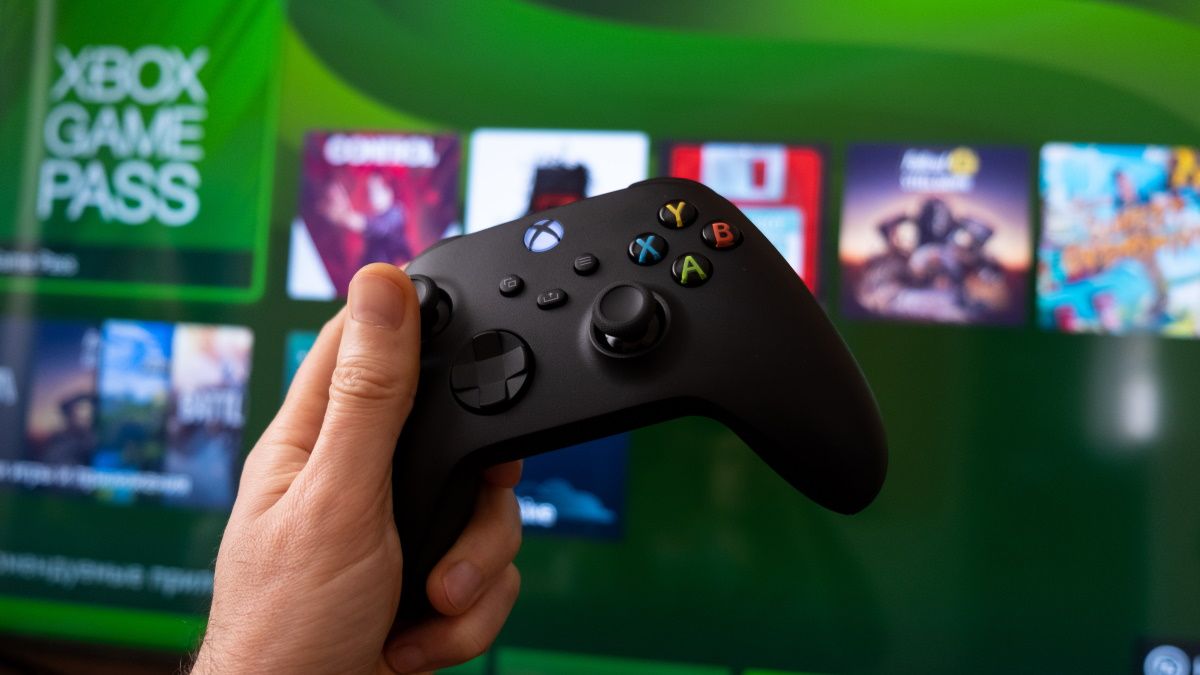 Uma mão segurando um controle do Xbox Series X na frente do Game Pass no console.