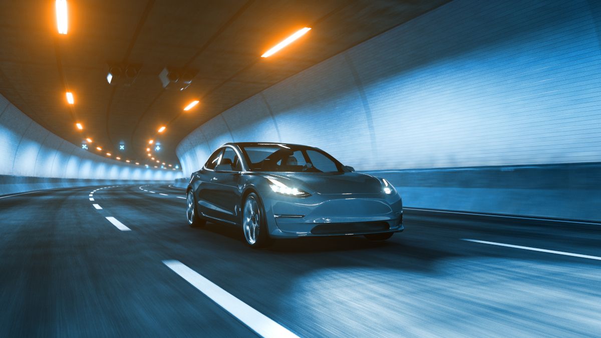 Um carro elétrico passando por um túnel sob luzes amarelas quentes.