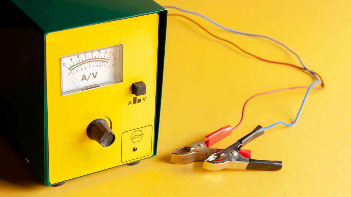 Um carregador de bateria de carro portátil em um fundo amarelo.