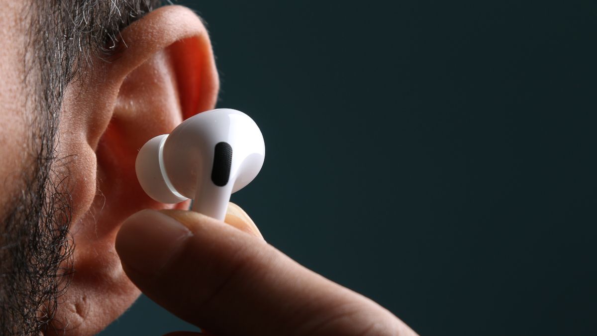Close de um Apple AirPod sendo colocado no ouvido de uma pessoa.