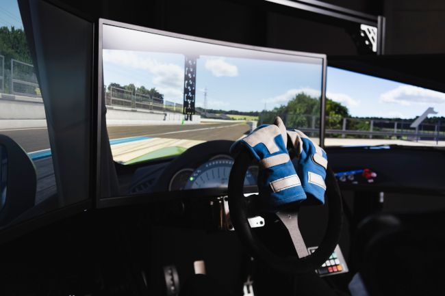 Interior de um simulador de corrida configurado com luvas de direção no volante.