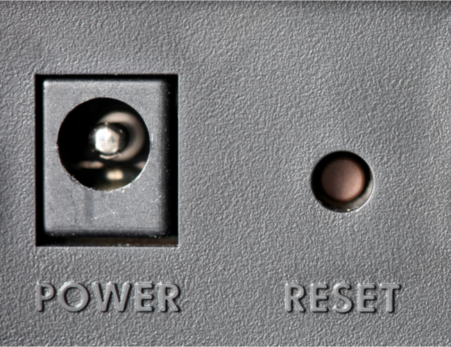 Um botão Reset inserido próximo a um conector de alimentação.