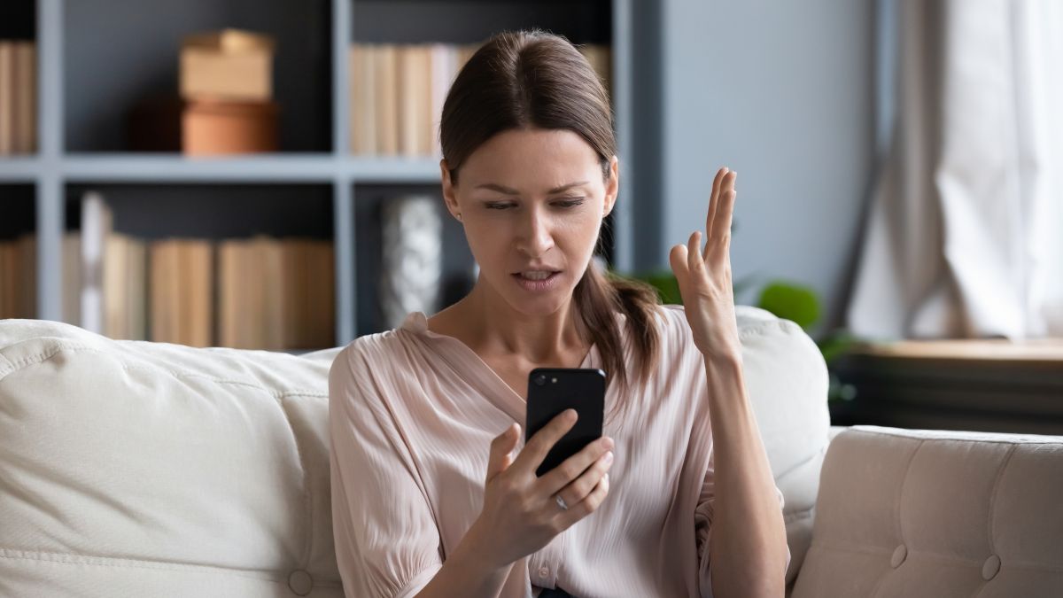 Mulher olhando para o telefone com uma expressão confusa ou frustrada.