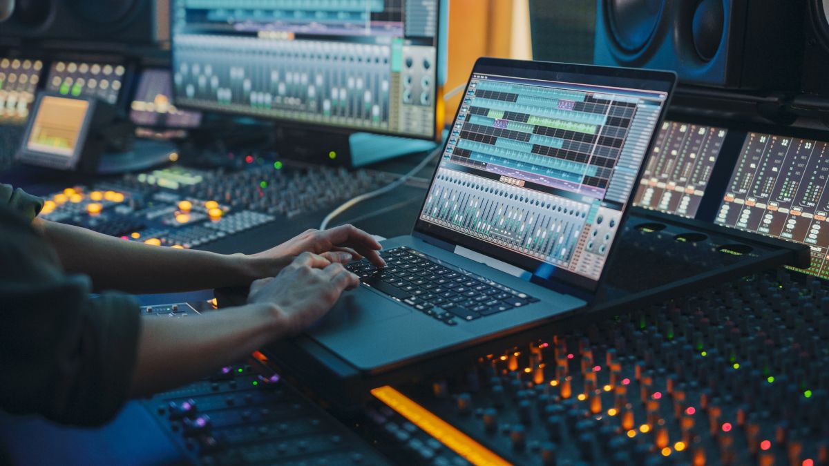 Pessoa trabalhando em um laptop em um estúdio de música moderno.