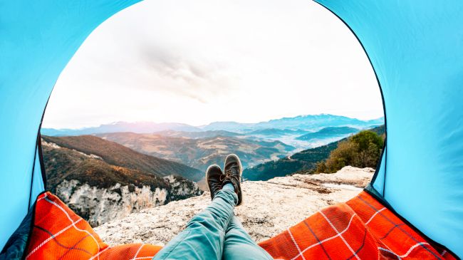 Foto do ponto de vista de uma montanha de dentro de uma barraca.