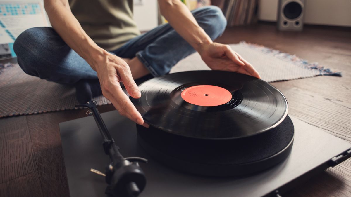 Mãos de mulher colocando um disco de vinil em um toca-discos.