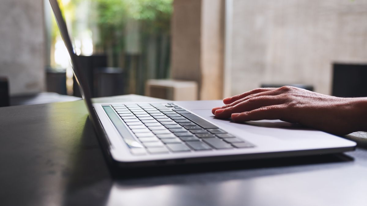 Close de um teclado de laptop com as mãos de uma pessoa nele.