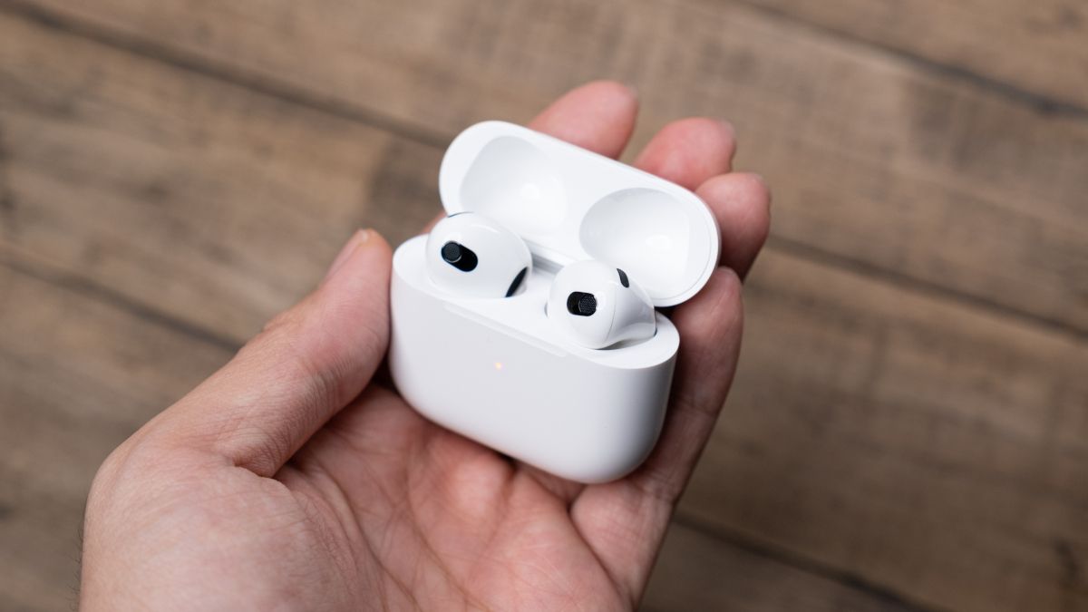 Apple AirPods em seu caso sendo segurado pela mão de uma pessoa.