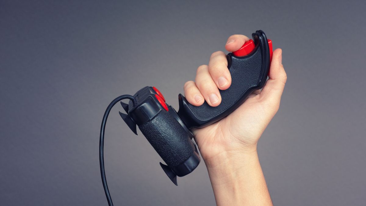 A mão de uma pessoa segurando um controlador de joystick retrô.