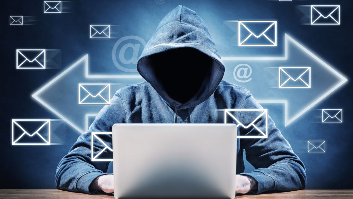 Pessoa com rosto obscurecido, usando um moletom com capuz e um laptop, com setas e ícones de e-mail flutuando ao seu redor.