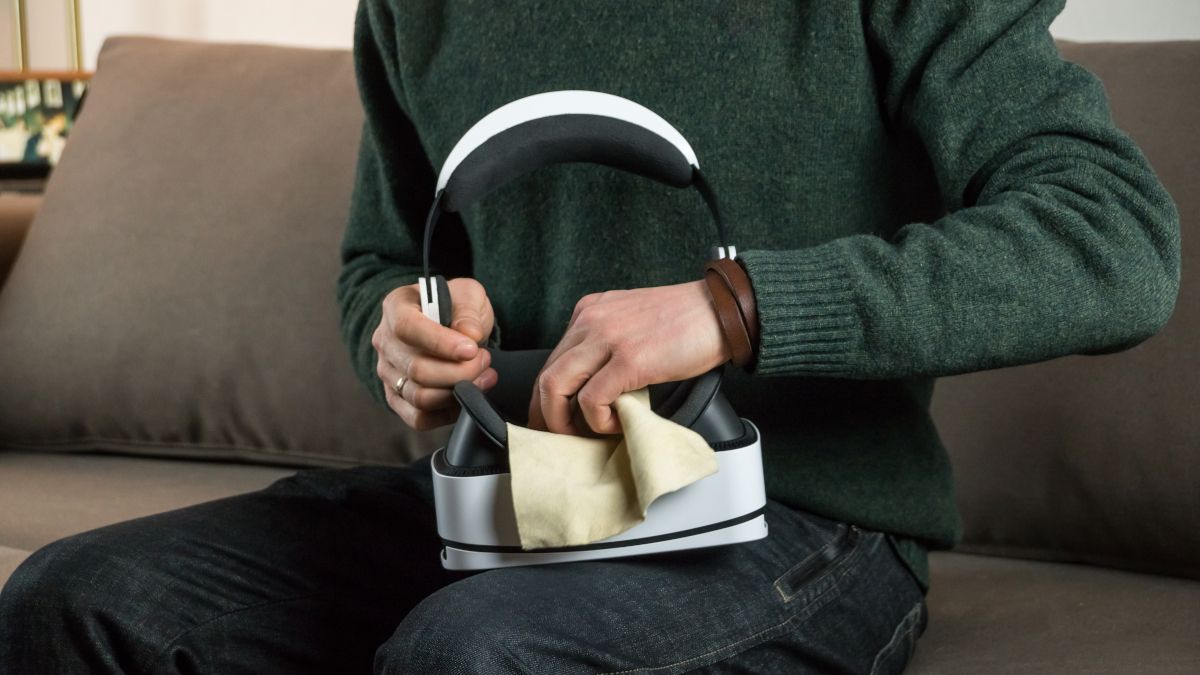 Um homem limpando um fone de ouvido de realidade virtual com um pano.