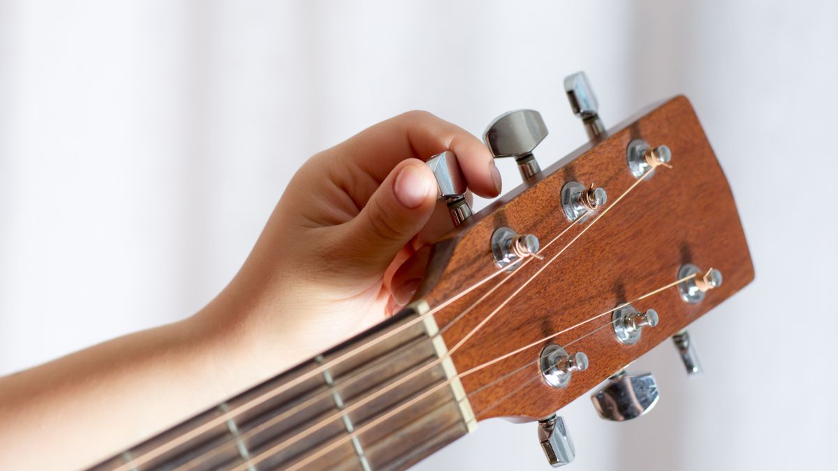 A mão de uma pessoa afinando uma guitarra.