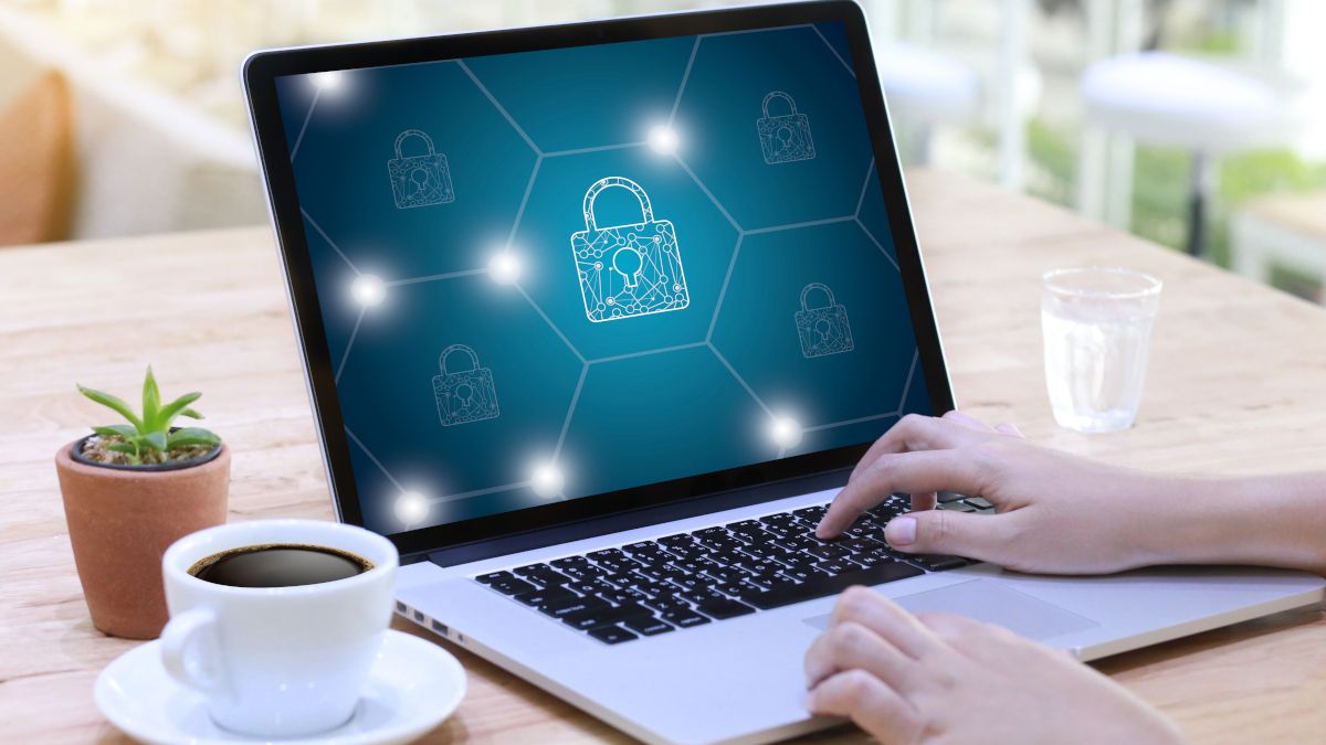 Mãos de uma pessoa usando um laptop com ícones de cadeado na tela, ilustrando o conceito de privacidade e segurança online.