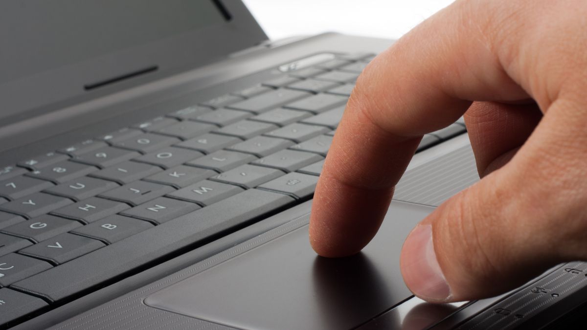 O dedo de uma pessoa no touchpad de um laptop.