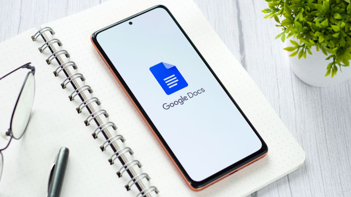 Um smartphone sobre um bloco de notas aberto e exibindo o logotipo do Google Docs.