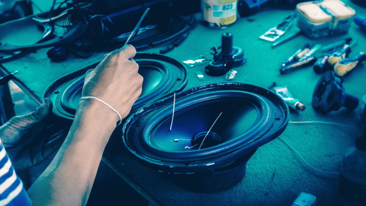 Um par de alto-falantes sendo consertados em uma bancada sob luz azul.