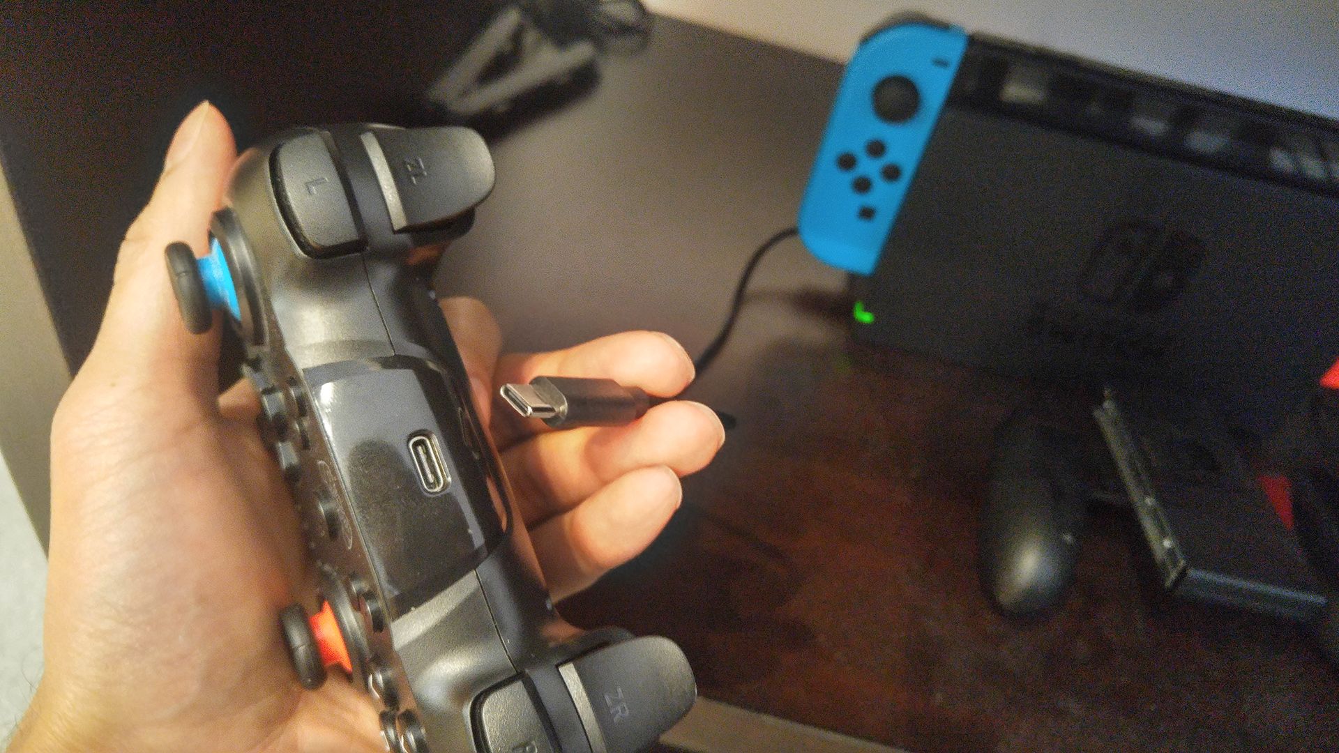 Segurando um cabo USB-C próximo à porta USB-C de um controle do Nintendo Switch.