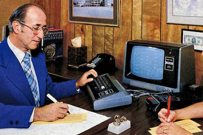 Um homem usando um TRS-80 em uma mesa.  Parte de um anúncio do TRS-80 Modelo I publicado na edição de novembro de 1977 da revista Byte.